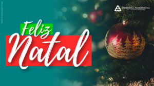 Foto com um letreiro escrito "Feliz Natal" em fundo vermelho e verde. A imagem é composta por uma árvore de natal, com enfoque em primeiro plano de uma bola decorativa. No topo da imagem há o logo do DAOR.